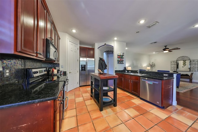 kitchen featuring sink, light tile patterned floors, appliances with stainless steel finishes, a center island, and decorative backsplash