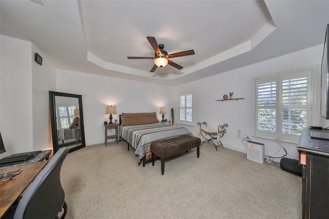 carpeted bedroom with a raised ceiling and ceiling fan