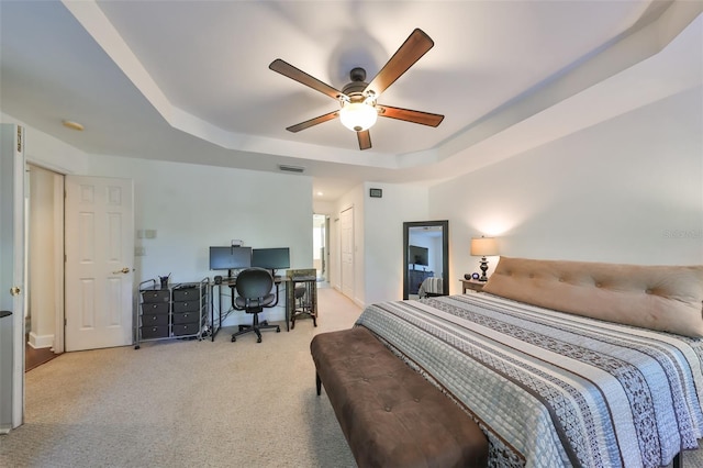 carpeted bedroom featuring ceiling fan and a raised ceiling