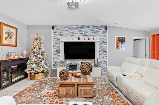 living room featuring a textured ceiling, a fireplace, light tile patterned flooring, and vaulted ceiling