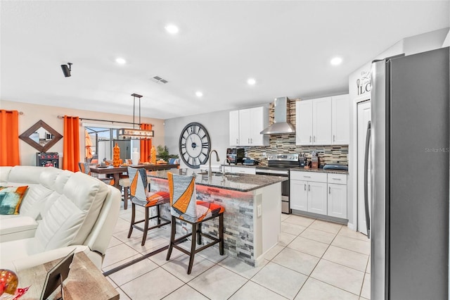 kitchen with wall chimney exhaust hood, a breakfast bar, stainless steel appliances, sink, and decorative light fixtures