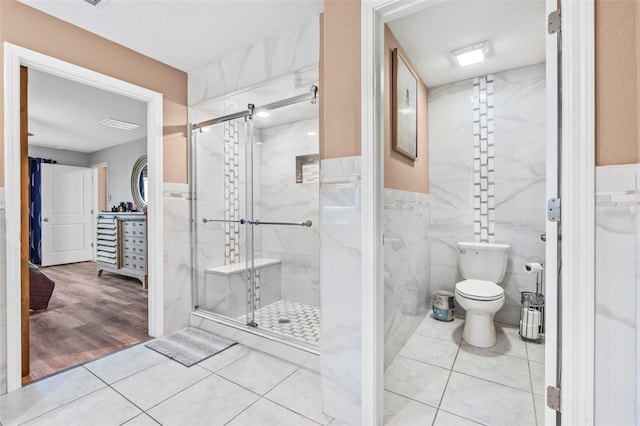 bathroom with tile walls, wood-type flooring, a shower with shower door, and toilet