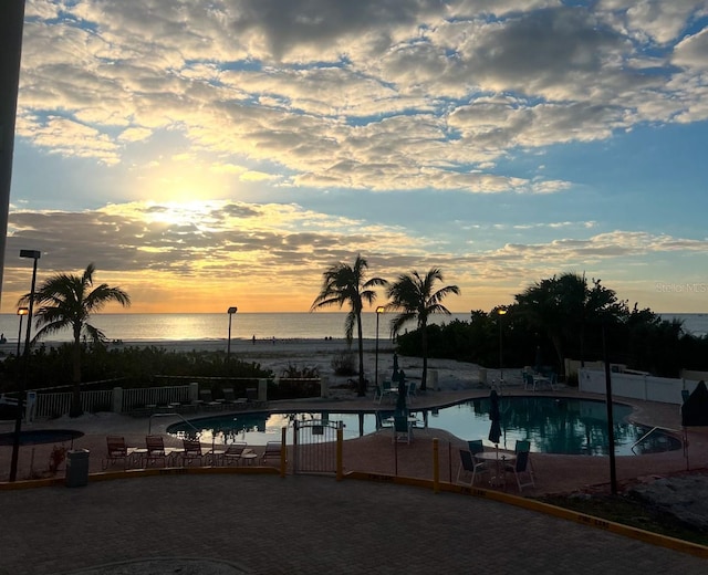 pool at dusk with a patio and a water view