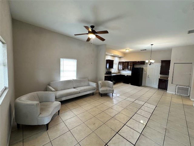 tiled living room with ceiling fan with notable chandelier