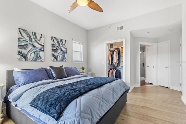 bedroom with light hardwood / wood-style floors, a spacious closet, a closet, and ceiling fan