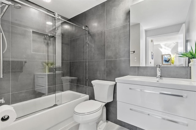 full bathroom with shower / bath combination with glass door, vanity, tile walls, and toilet