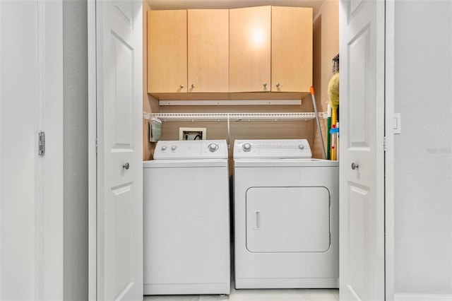 washroom featuring washing machine and clothes dryer and cabinets