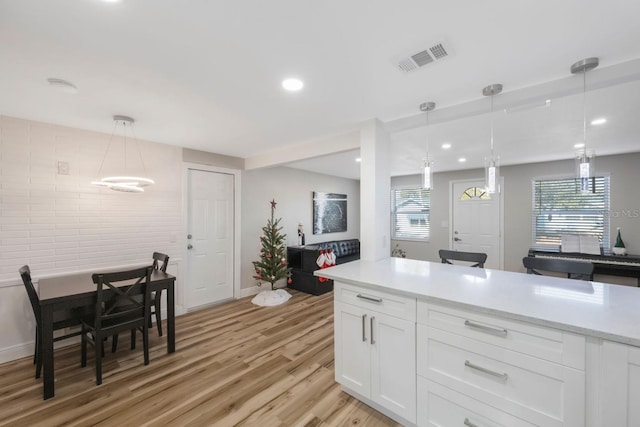 kitchen featuring light wood-type flooring, white cabinetry, and hanging light fixtures