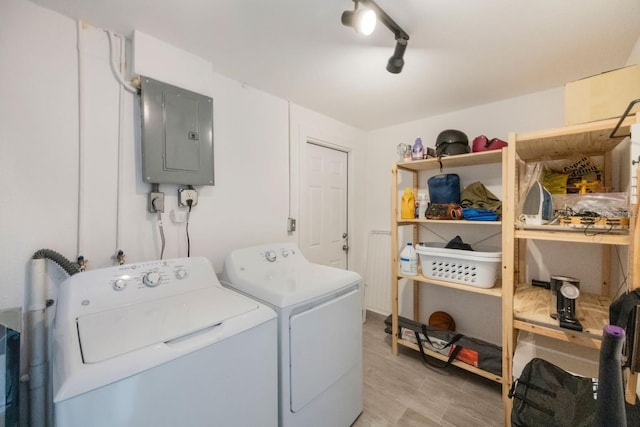 washroom featuring electric panel, washer and dryer, track lighting, and light hardwood / wood-style floors