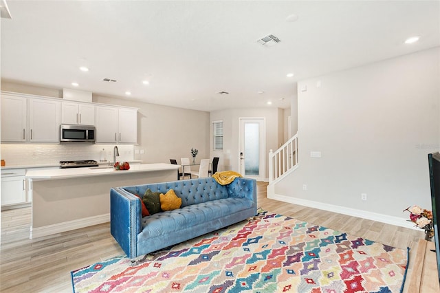 living room with light hardwood / wood-style flooring and sink