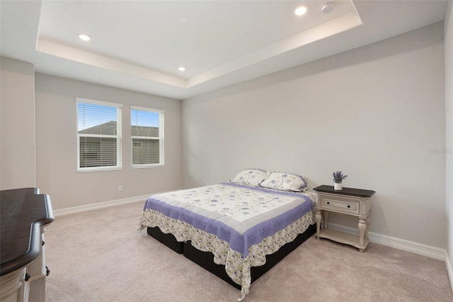 bedroom featuring light carpet and a raised ceiling