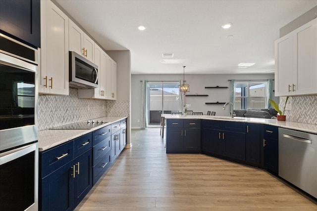 kitchen featuring a wealth of natural light, white cabinets, hanging light fixtures, and appliances with stainless steel finishes