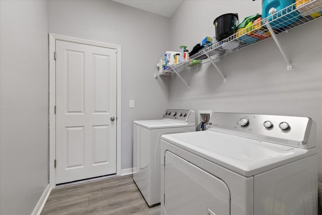 clothes washing area with washer and dryer and light wood-type flooring