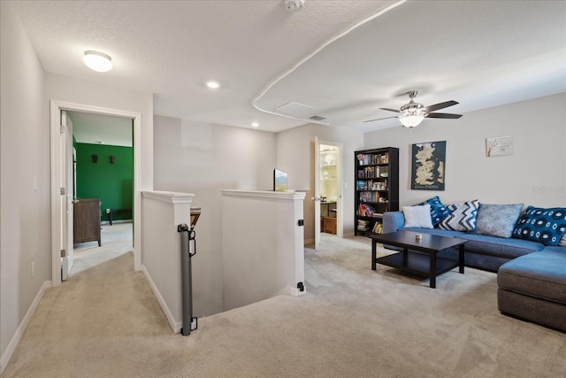 carpeted living room featuring ceiling fan and a textured ceiling