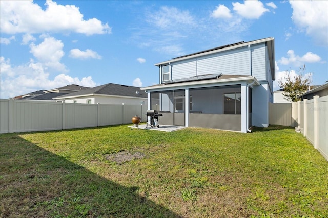 back of property with a sunroom, solar panels, and a lawn