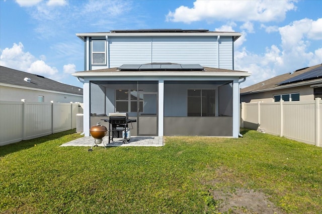 back of property with a lawn, central air condition unit, a sunroom, and solar panels