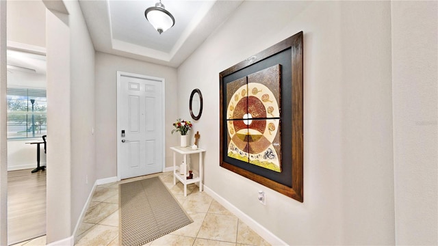 foyer featuring light tile patterned floors and a tray ceiling