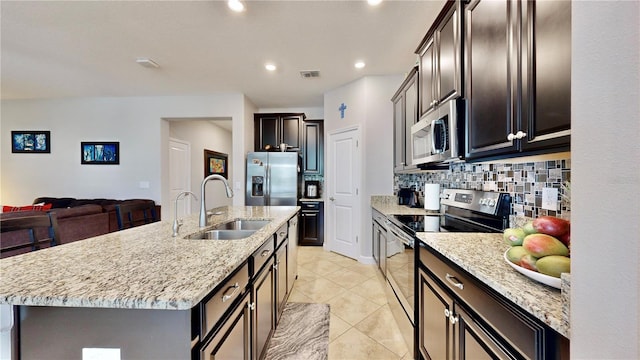 kitchen with sink, backsplash, a kitchen island with sink, light tile patterned floors, and appliances with stainless steel finishes