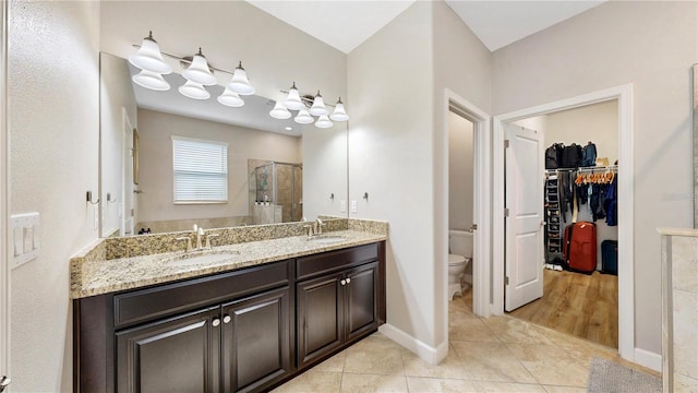 bathroom featuring toilet, vanity, tile patterned floors, and a shower with door