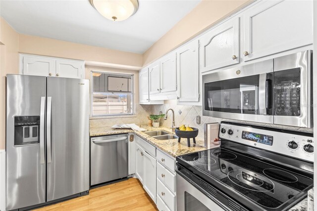 kitchen featuring backsplash, sink, appliances with stainless steel finishes, light hardwood / wood-style floors, and white cabinetry