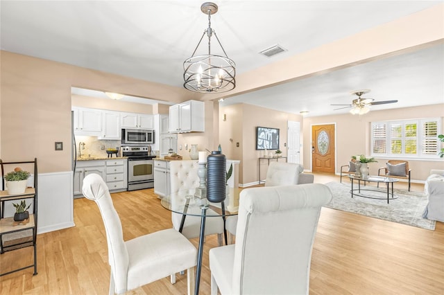 dining area with ceiling fan with notable chandelier and light wood-type flooring