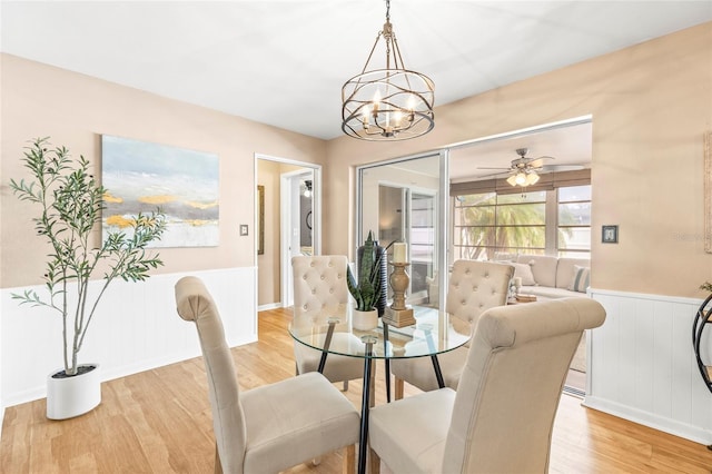 dining room featuring ceiling fan with notable chandelier and light hardwood / wood-style floors