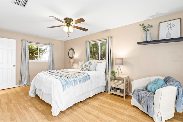 bedroom featuring ceiling fan, light hardwood / wood-style floors, and multiple windows