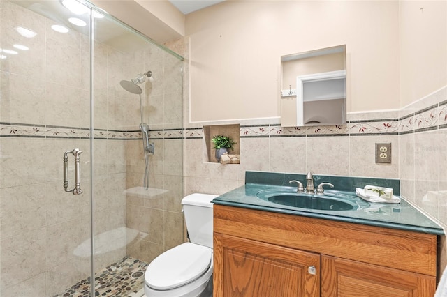 bathroom with walk in shower, vanity, tile walls, and toilet