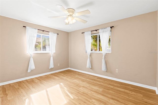 empty room featuring ceiling fan, plenty of natural light, and hardwood / wood-style floors