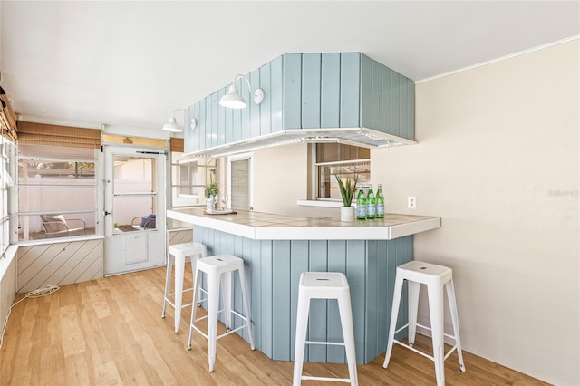 kitchen featuring a kitchen bar, kitchen peninsula, and light wood-type flooring