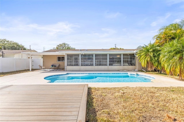 view of pool with a sunroom, a patio, and a wooden deck