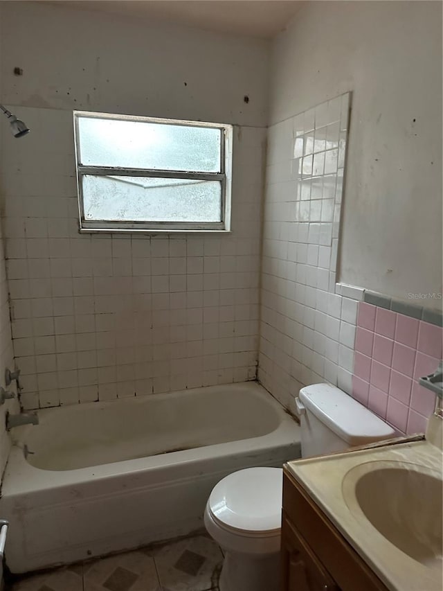 full bathroom featuring vanity, toilet, tile walls, and tiled shower / bath