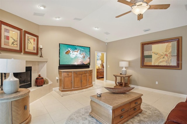 tiled living room featuring ceiling fan, a tile fireplace, and vaulted ceiling