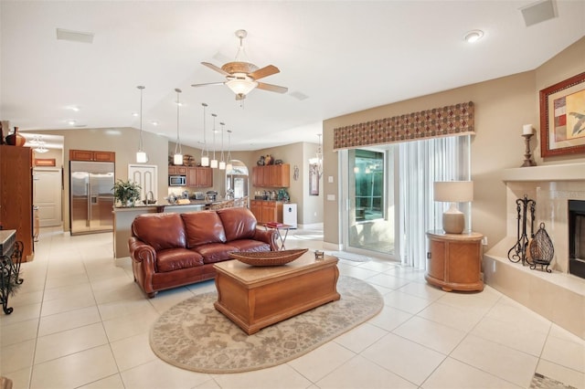 living room with ceiling fan, light tile patterned floors, a premium fireplace, and vaulted ceiling