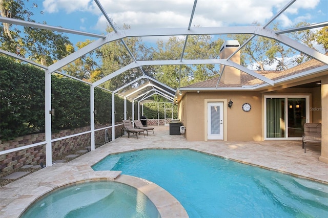 view of pool featuring glass enclosure, an in ground hot tub, and a patio