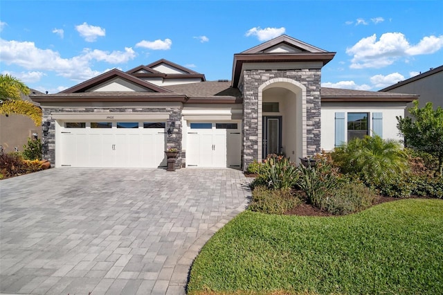 view of front of home with a garage, stone siding, decorative driveway, a front lawn, and stucco siding