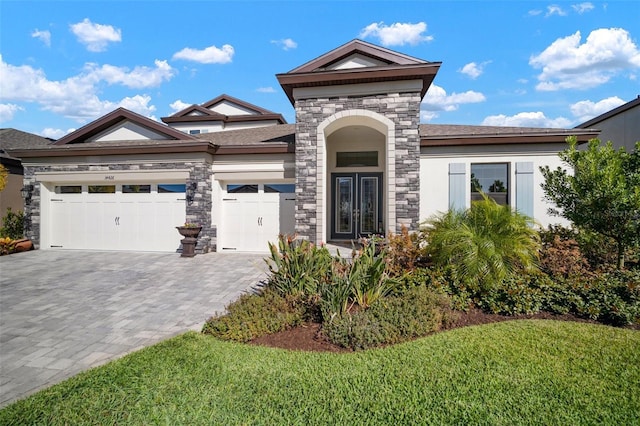 view of front of home featuring decorative driveway, stucco siding, a garage, stone siding, and a front lawn