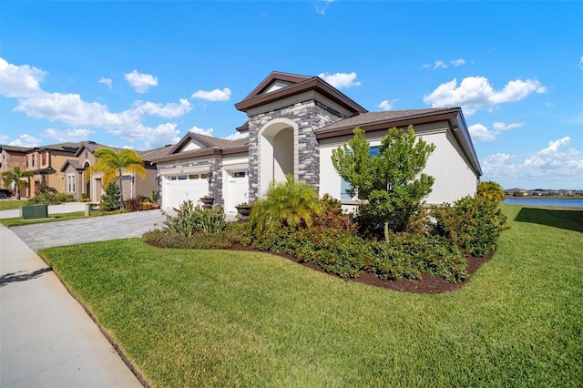 view of front of property with an attached garage, stone siding, decorative driveway, stucco siding, and a front lawn