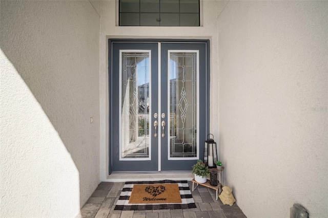 view of exterior entry with stucco siding and french doors