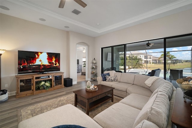 living area with visible vents, arched walkways, a ceiling fan, wood finished floors, and crown molding