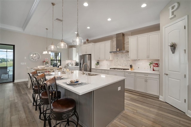 kitchen featuring light countertops, wall chimney range hood, and white cabinetry