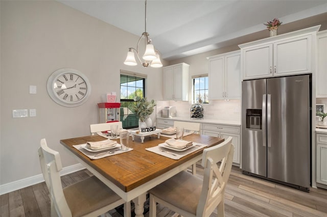 dining space with baseboards, light wood-type flooring, and a healthy amount of sunlight