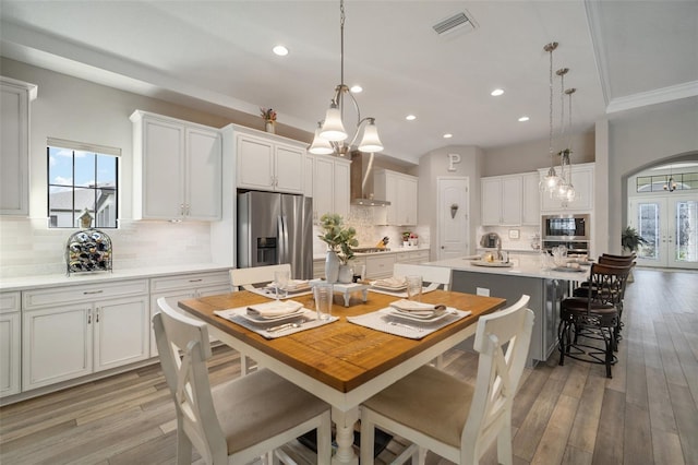 dining space with light wood finished floors, visible vents, a wealth of natural light, and french doors