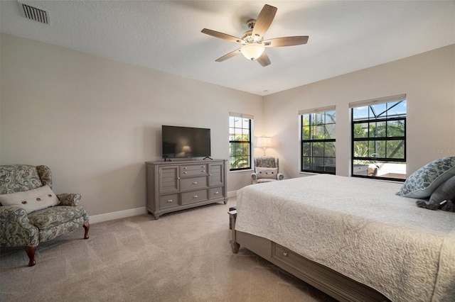 bedroom featuring baseboards, ceiling fan, visible vents, and light colored carpet