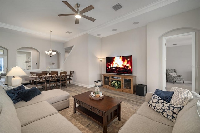 living room with crown molding, light wood-type flooring, visible vents, and baseboards