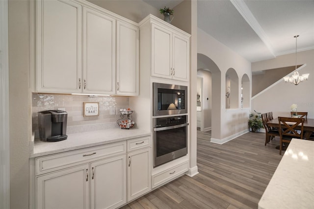 kitchen featuring light wood-style flooring, decorative backsplash, white cabinetry, stainless steel oven, and black microwave