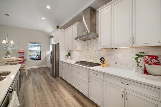 kitchen featuring stainless steel appliances, white cabinetry, hanging light fixtures, backsplash, and wall chimney exhaust hood