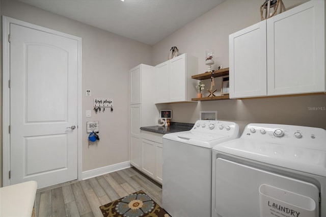 clothes washing area with cabinet space, baseboards, light wood-style floors, and washer and dryer