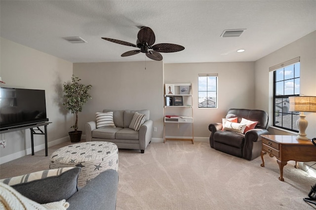 living room featuring baseboards, a textured ceiling, visible vents, and light colored carpet