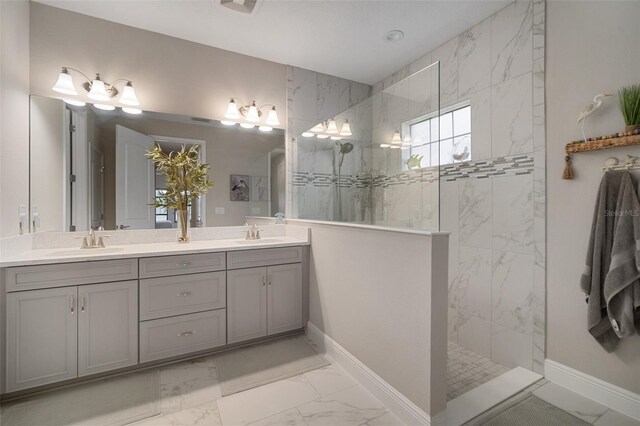 bathroom with marble finish floor, double vanity, walk in shower, and a sink